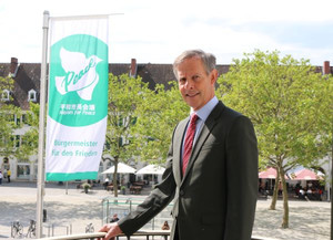 Foto: Oberbürgermeister Udo Bausch mit der Flagge der Mayors for Peace (Foto: Stadt Rüsselsheim am Main)