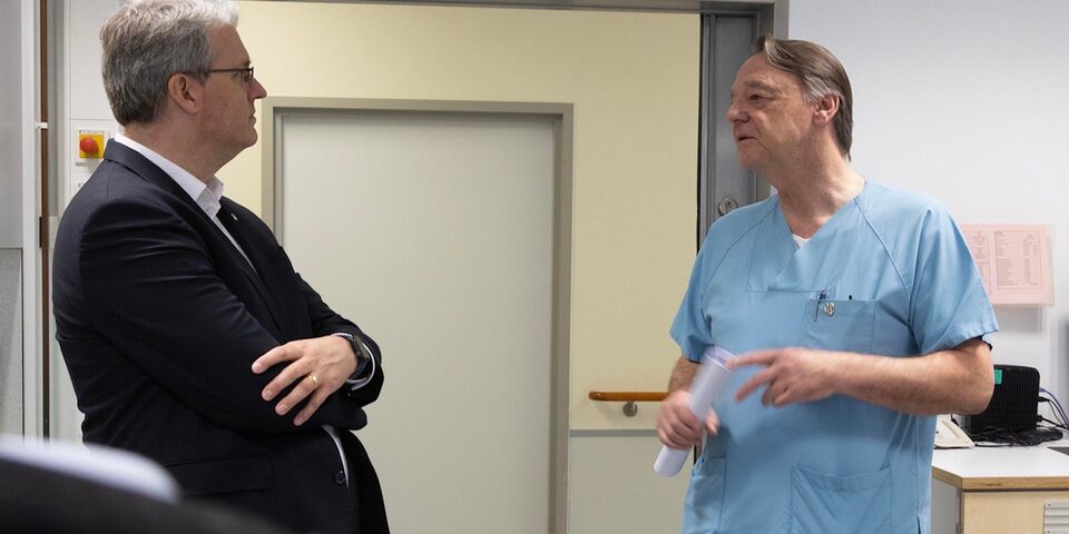 Oberbürgermeister Patrick Burghardt im Gespräch mit dem Chefarzt der Urologie Dr. Guido Platz. Beide stehen in einem Gang.