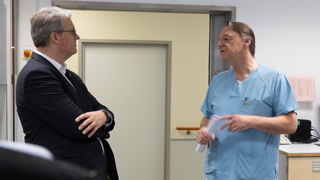 Oberbürgermeister Patrick Burghardt im Gespräch mit dem Chefarzt der Urologie Dr. Guido Platz. Beide stehen in einem Gang.