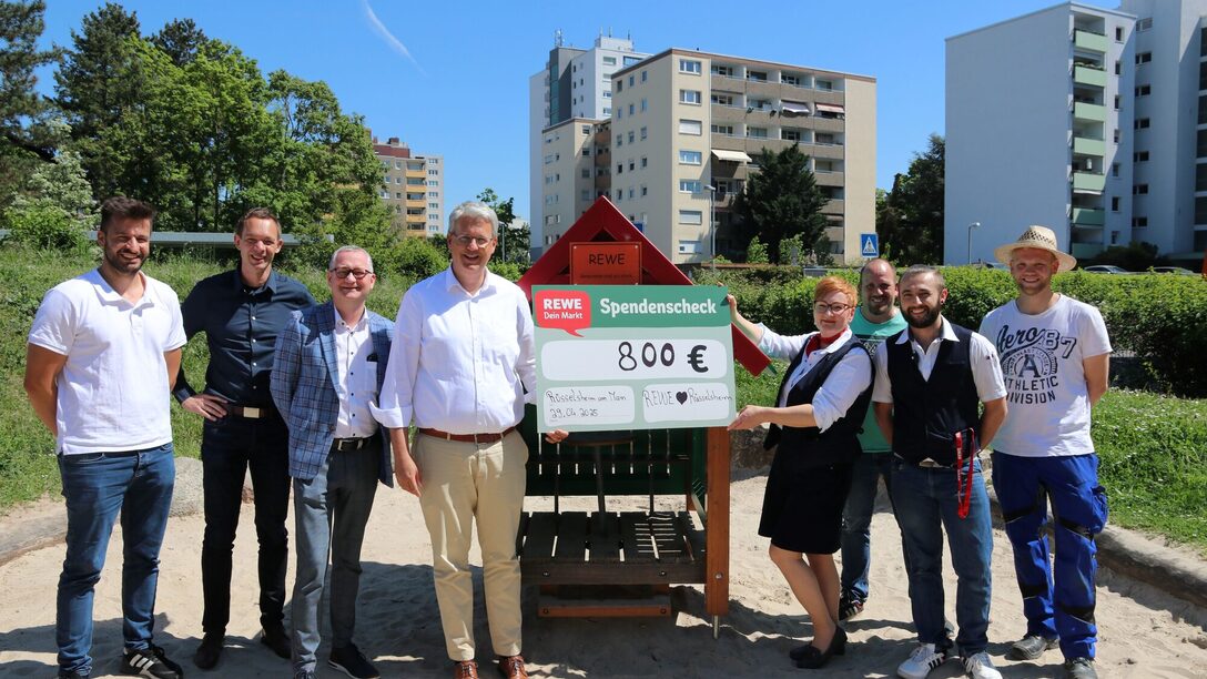 Das Rewe-Team übergibt vor dem neuen Spielhaus einen Spendencheck.