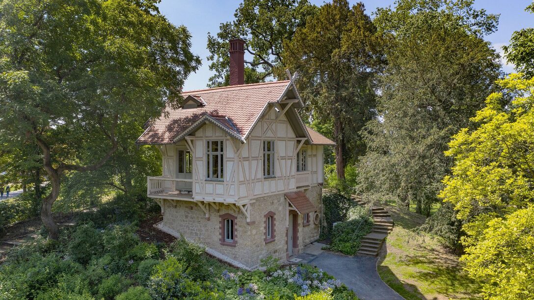 Die alte Mühle im Verna-Park steht zwischen grünen Bäumen.