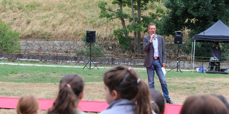 Stadtrat Valerius vor einem roten Teppich und zuhörenden Kindern.