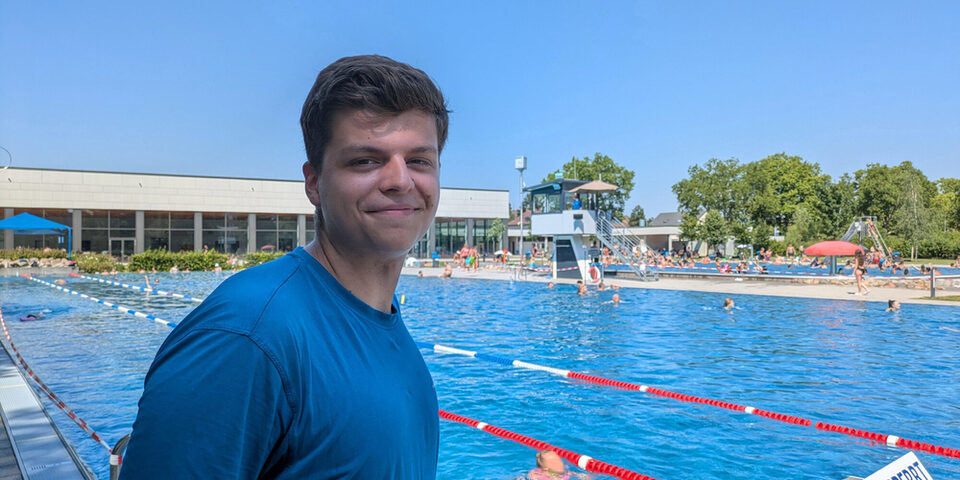 Nils Seewald steht im blauen T-Shirt vor den Startblöcken des Schwimmerbeckens im Freibad An der Lache.