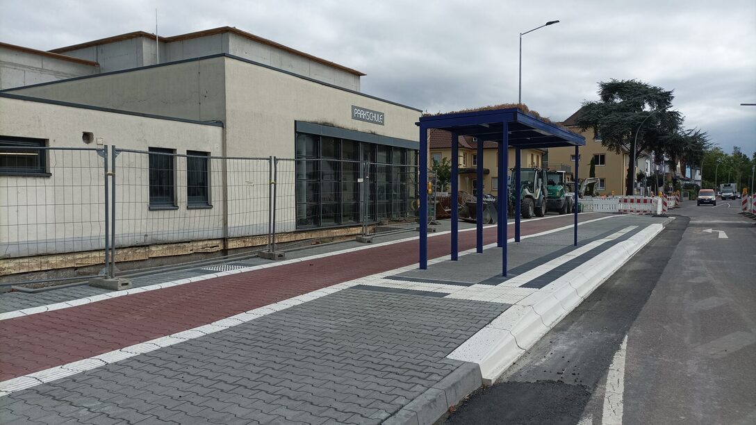 Frisch gepflasteter Gehweg mit taktilen Elementen und barrierefreier Bushaltestelle.