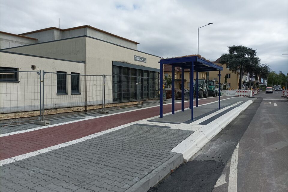 Frisch gepflasteter Gehweg mit taktilen Elementen und barrierefreier Bushaltestelle.