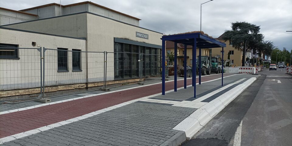 Frisch gepflasteter Gehweg mit taktilen Elementen und barrierefreier Bushaltestelle.