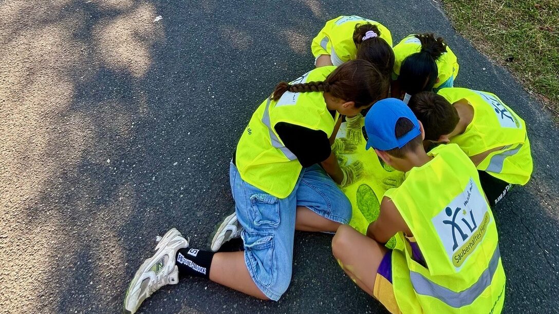 Kinder malen gelbe Füße auf den Asphalt