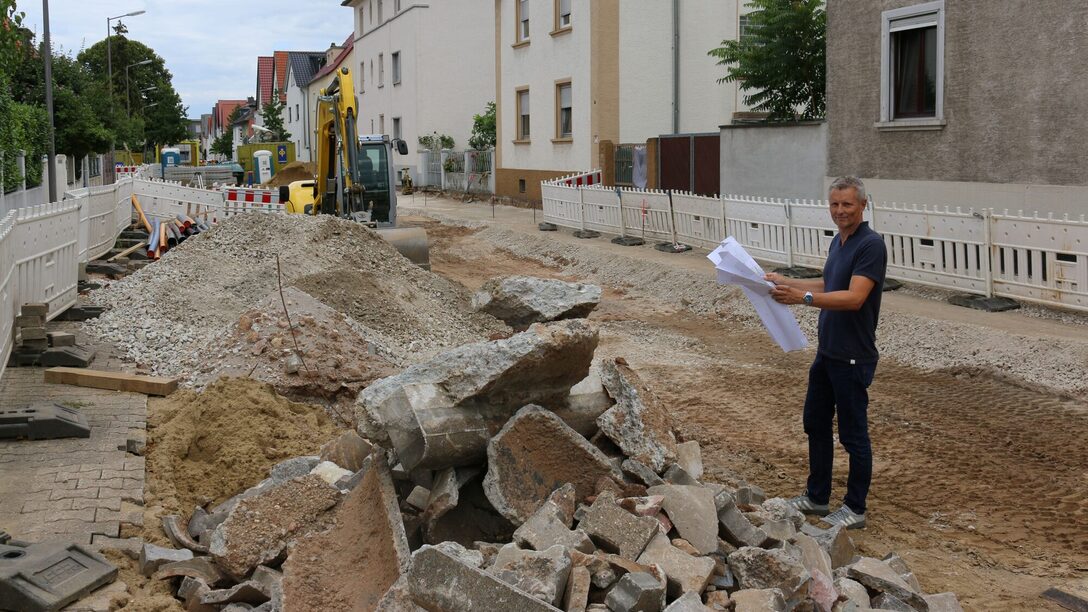 Der Leiter der Kanalabteilung auf der aufgerissen Straße mit Bruchsteinen und Kieshaufen.