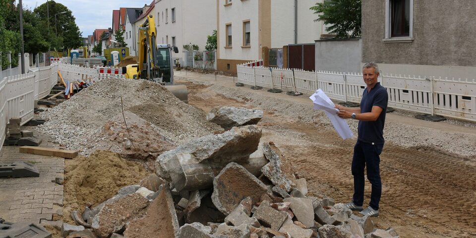 Der Leiter der Kanalabteilung auf der aufgerissen Straße mit Bruchsteinen und Kieshaufen.
