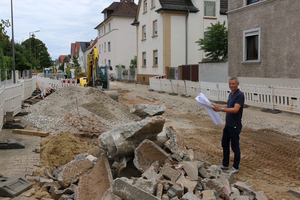 Der Leiter der Kanalabteilung auf der aufgerissen Straße mit Bruchsteinen und Kieshaufen.