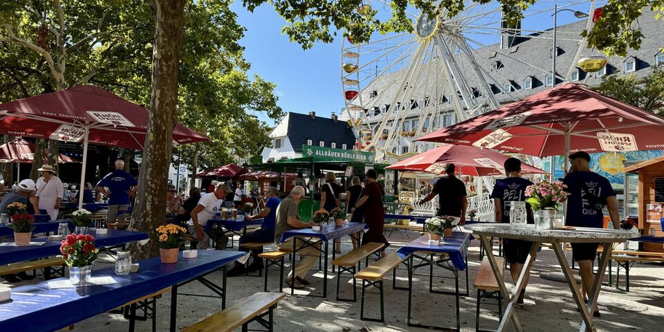 Blick auf den Kerbetreff am Marktplatz mit Bierzeltgarnituren und Verkaufsständen. Im Hintergrund ein Riesenrad vor dem Rathaus.