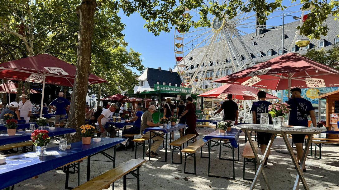 Blick auf den Kerbetreff am Marktplatz mit Bierzeltgarnituren und Verkaufsständen. Im Hintergrund ein Riesenrad vor dem Rathaus.