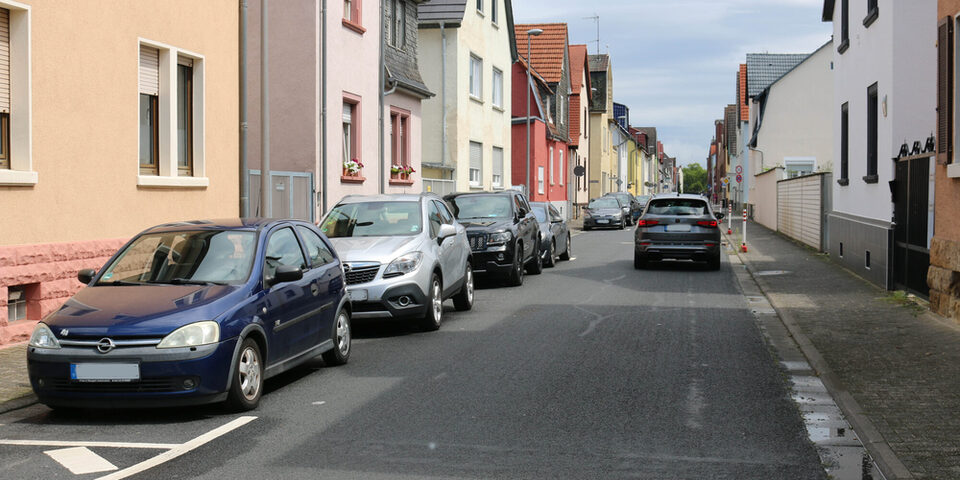 Ein Auto fährt in Richtung Bahnhof und Autos parken in der Gegenrichtung.
