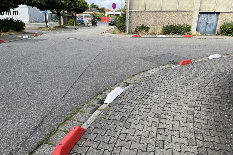 Rote und weiße Schwellen sichern den Gehweg ab.