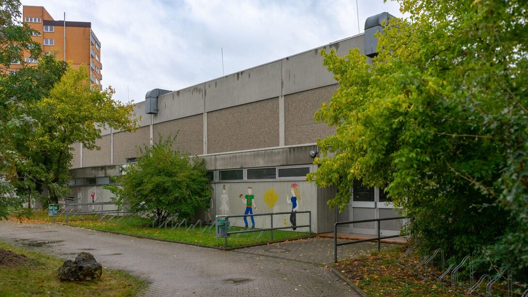 Eingang zur Sporthalle mit Gemälden an der Seitenwand.