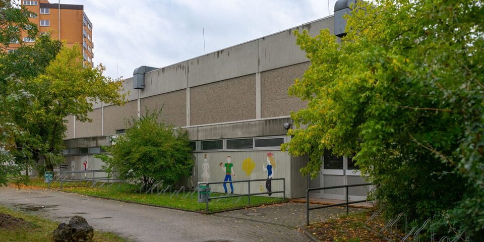Eingang zur Sporthalle mit Gemälden an der Seitenwand.
