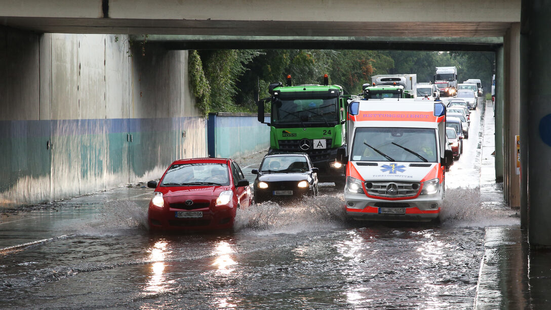 Autos fahren durch tiefes Wasser in der Unterführung Rugbyring.