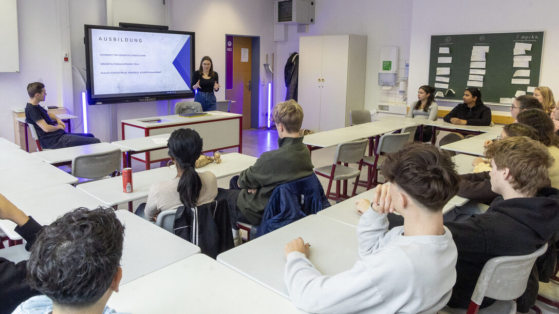 Unternehmen stellen sich vor: Schüler sitzen in einem Klassenraum. An einem Whiteboard läuft eine Präsentation.