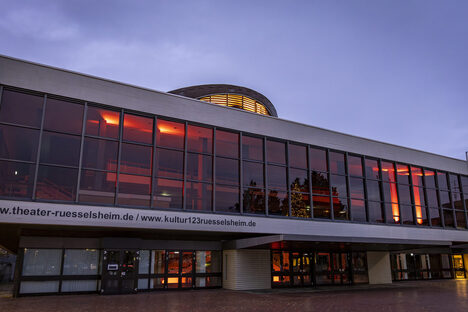 Blick auf das Theater Rüsselsheim, die Innenräume sind im Rahmen der "Orange Days" orange beleuchtet.