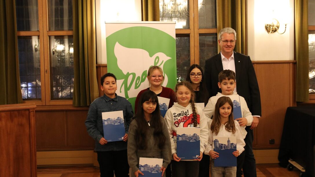 Kinder und Jugendliche stehen neben dem Oberbürgermeister und zeigen ihre Urkunden.