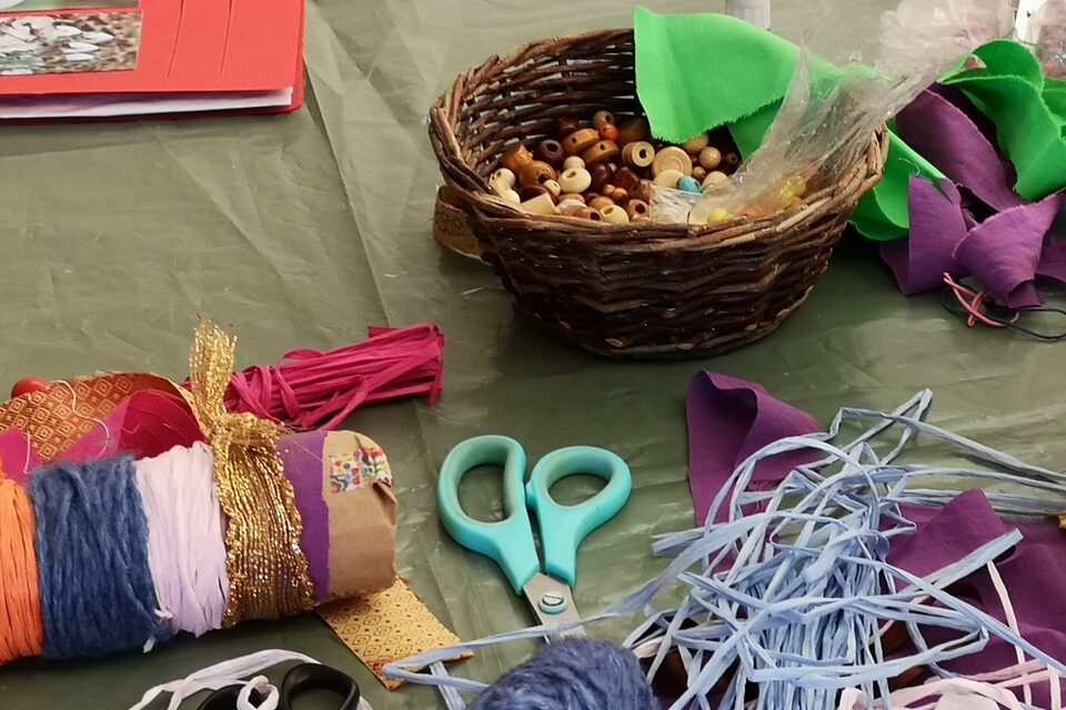 Bastelmaterialien wie Schere, Bänder und Perlen liegen auf einem Tisch bereit.