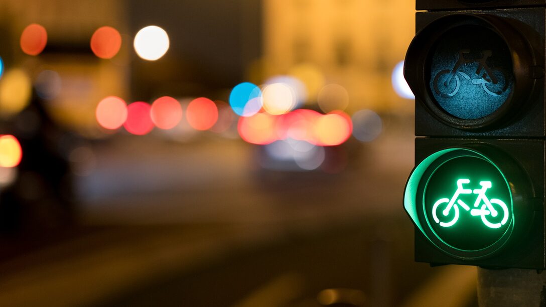 Grüne Ampel mit Fahrrad-Symbol. Lichter im Hintergrund.