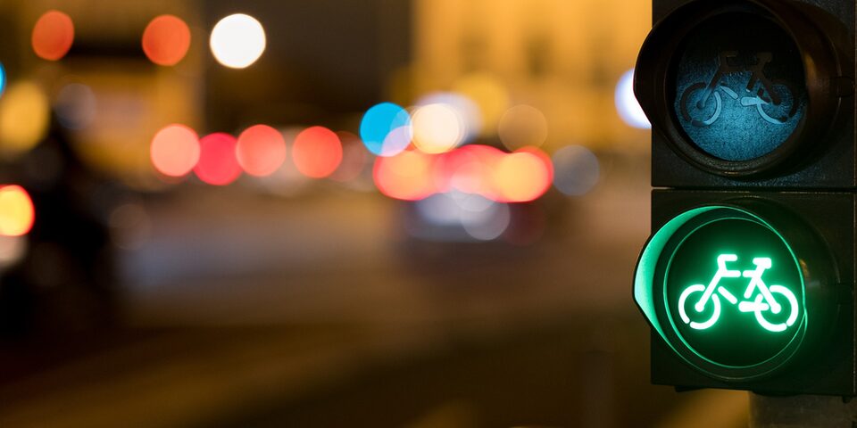 Grüne Ampel mit Fahrrad-Symbol. Lichter im Hintergrund.