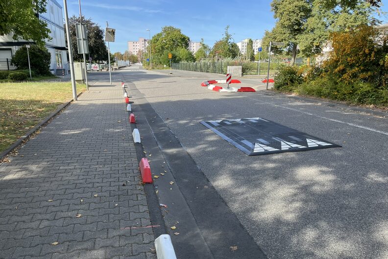 Erhöhungen am Bordstein sichern den Gehweg ab, ein Aufbau auf der Straße sorgt für Geschwindigkeitsreduzierung