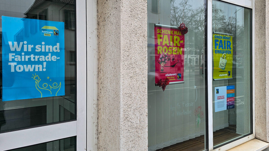 Das Schaufenster des Umweltamts mit Plakaten zum Aktionsmonat Fairbruary. Auf einem Plakat steht "Wir sind Fairtrade-Town", auf einem anderen "Schenk mal Fair-Rosen".