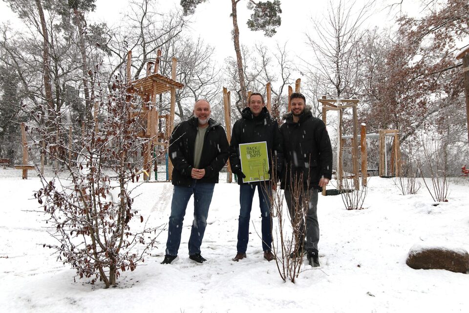 Vertreter der Stadt und des Städteservices im Schnee vor Strauchpflanzungen, bei denen Pflanzenkohle verwendet wurde.