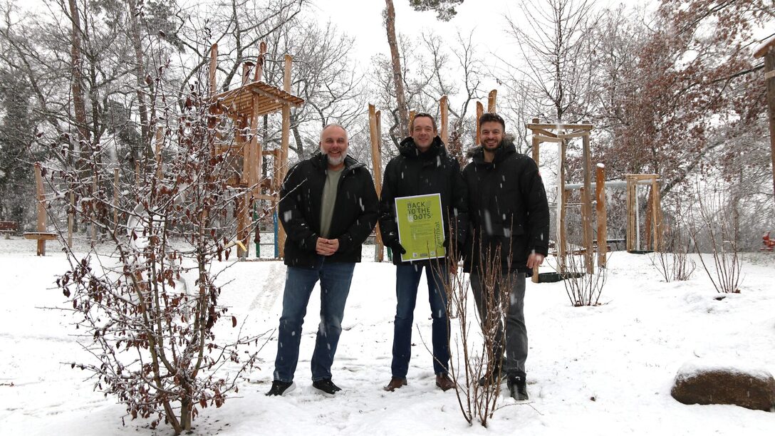 Vertreter der Stadt und des Städteservices im Schnee vor Strauchpflanzungen, bei denen Pflanzenkohle verwendet wurde.