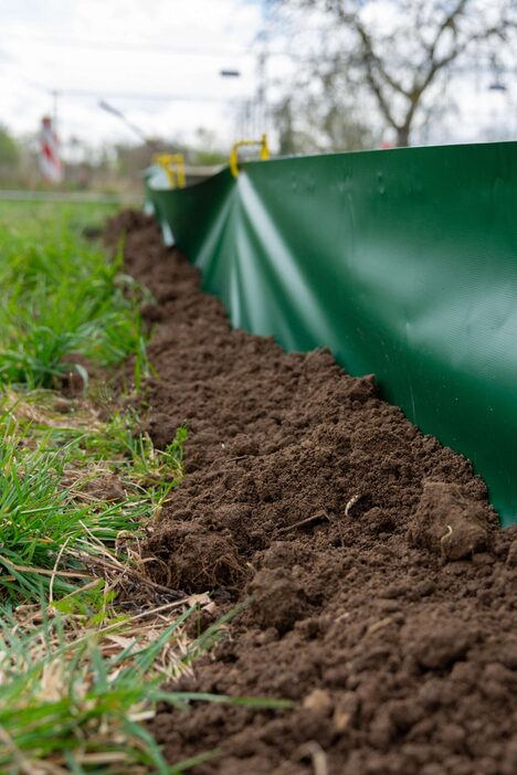 Ein dunkelgrüner Zaum mit Plastikfolien stoppt Reptilien, damit sie zu den Auslässen weitergehen.
