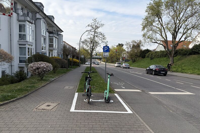 Ein E-Scooter und ein Mietfahrrad in einer neu eingerichteten Abstellzone