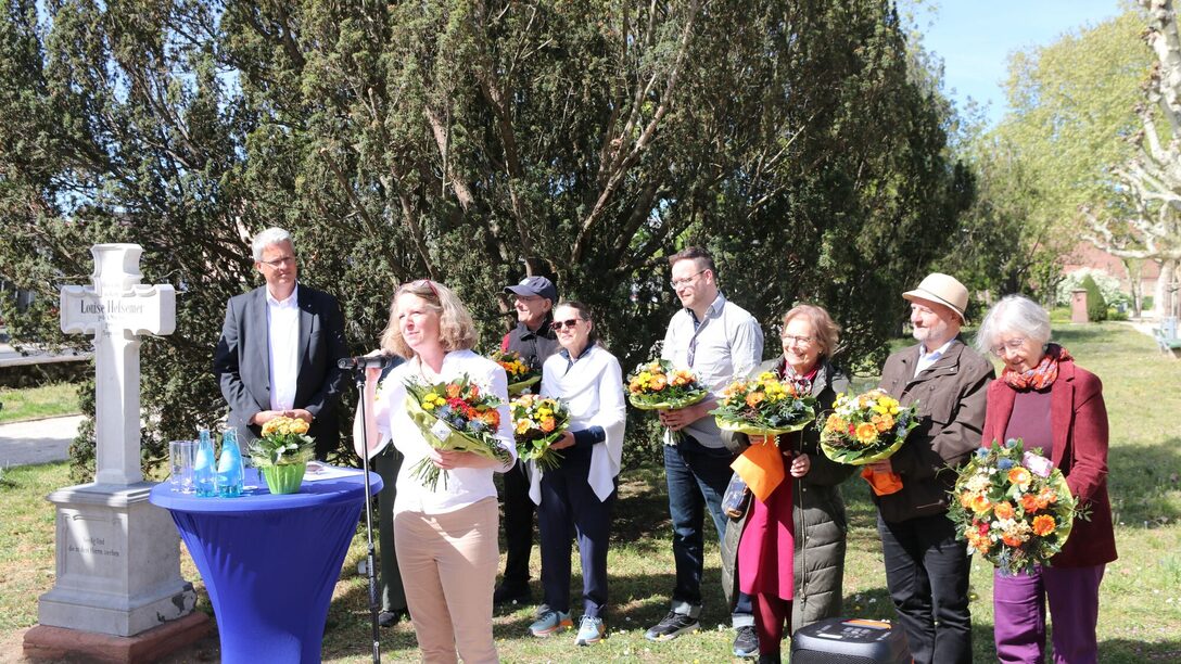 Neben dem Grabstein stehen Oberbürgermeister Burghardt und Nachfahren von Luise Heßemer