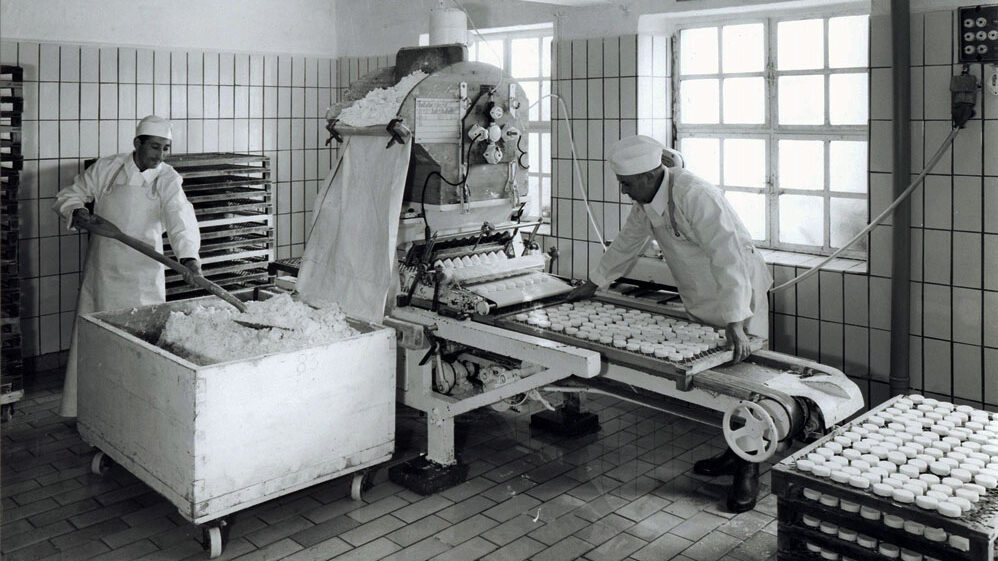 Mitarbeiter arbeiten an einer Formmaschine für Handkäs'