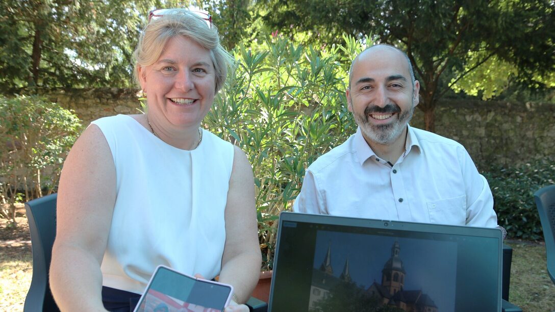 Tanja Koerwer zeigt neben Bürgermeister Karakaya Fotos vom Urlaub ohne Koffer