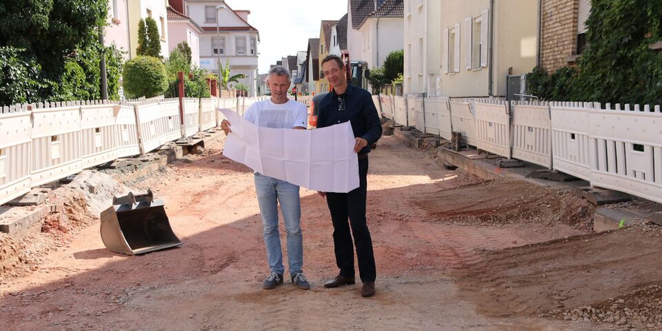 Abteilungsleiter Kanal und Baudezernent schauen sich auf der Baustelle den Bauplan an.