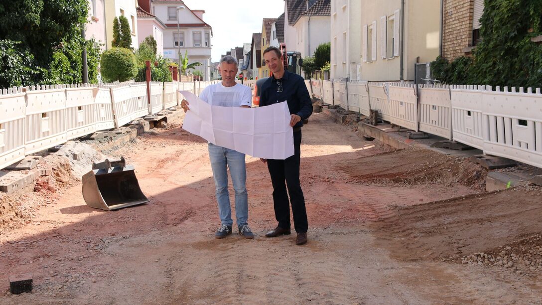 Abteilungsleiter Kanal und Baudezernent schauen sich auf der Baustelle den Bauplan an.