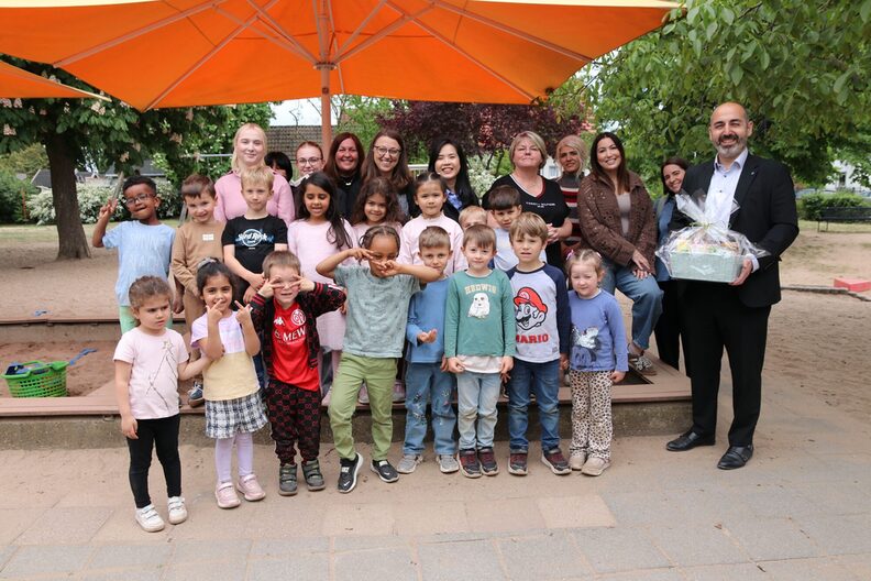 Gruppenfoto mit Bürgermeister Murat Karakaya mit Kindergartenkindern und den pädagogischen Fachkräften der Kindertagessätte Zamenhofstraße