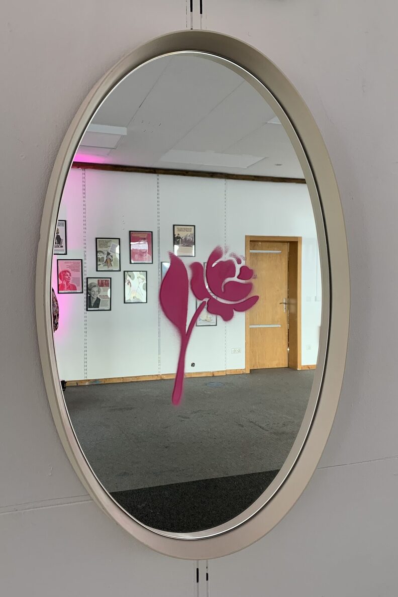 Ein Spiegel mit einer Rose - das Spiegelbild zeigt Werke der Ausstellung