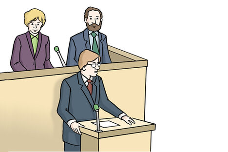 Ein Mann in einem Anzug hält an einem Rednerpult eine Rede.