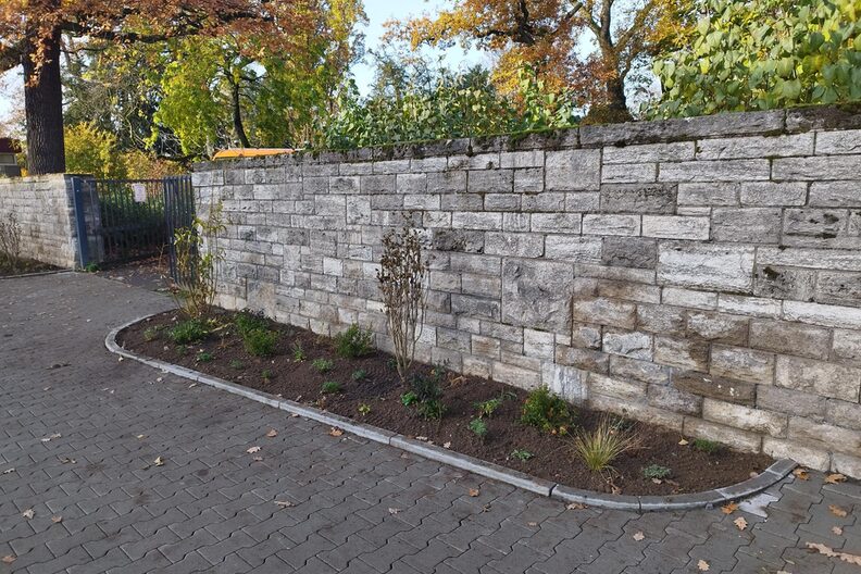 Neues Pflanzbeet vor dem Eingang zum Stadtpark, dahinter sieht man die Mauer, die den Stadtpark umgibt.