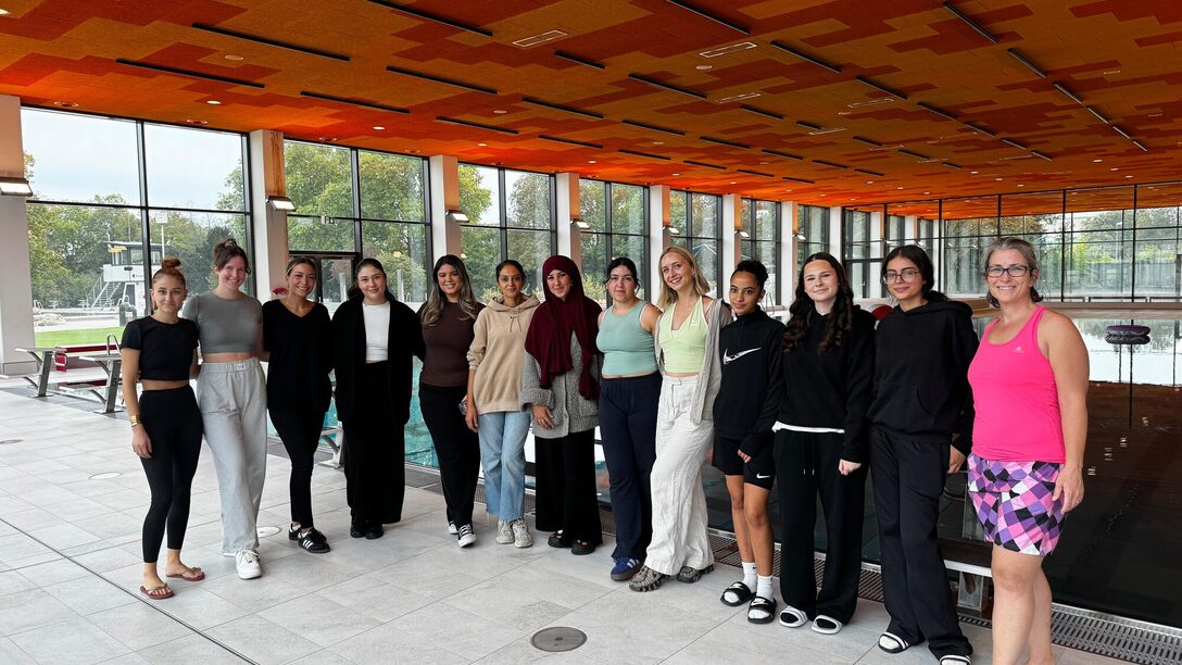 Die Betreuerinnen der Poolparty stehen im Schwimmbad vor dem Becken.