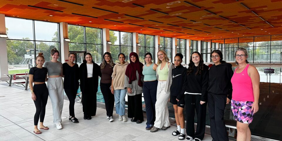 Die Betreuerinnen der Poolparty stehen im Schwimmbad vor dem Becken.