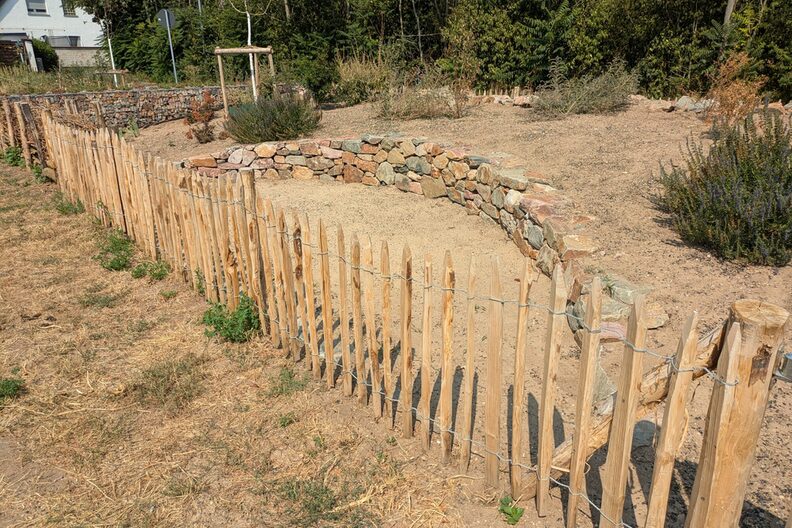 Andere Perspektive der Trockenmauer, im Vordergrund ein Zaun