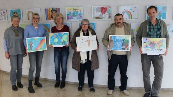 Jurymitglieder halten die ausgewählten Kunstwerke hoch