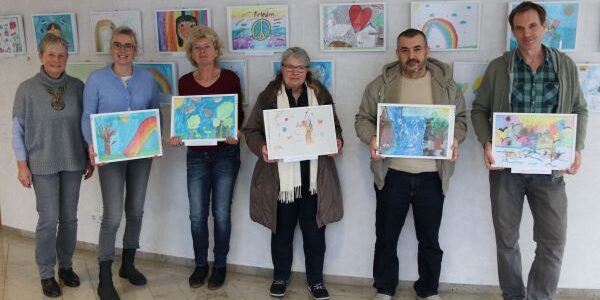 Jurymitglieder halten die ausgewählten Kunstwerke hoch