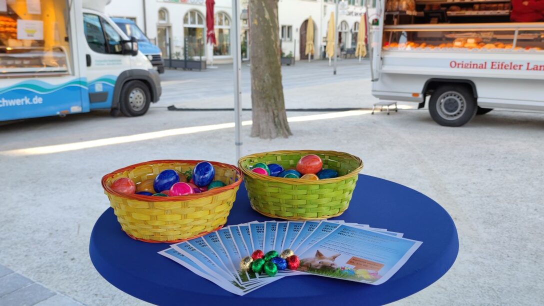 Kürbe mit Ostereiern auf einem Tisch bei der Osteraktion, im Vordergrud liegen Infoblätter und Schokoladeneier auf dem Tisch