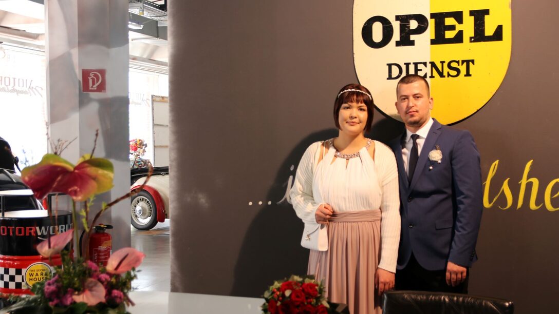 Diana und Kledjus vor einem historischen Opel-Emblem in der MOTORWORLD