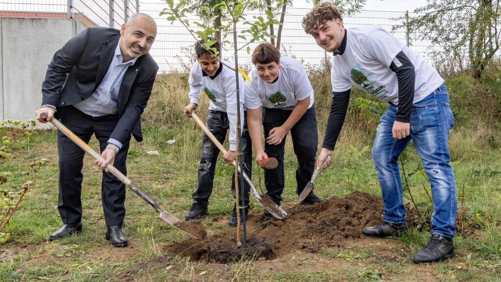 Bürgermeister Murat Karakaya pflanzt mit drei Schülern der Sophie-Opel-Schule einen Apfelbaum ein